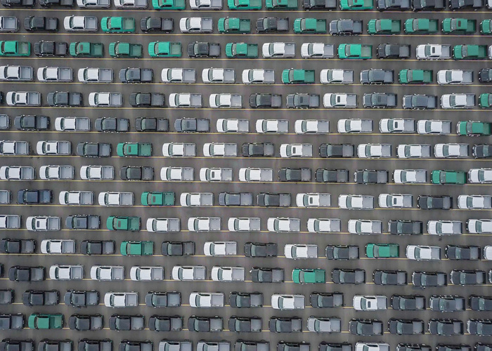 An aerial shot of green, white and black fleet vehciles parked in lines