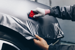 A close up of a man carefully installing fleet branding onto a car